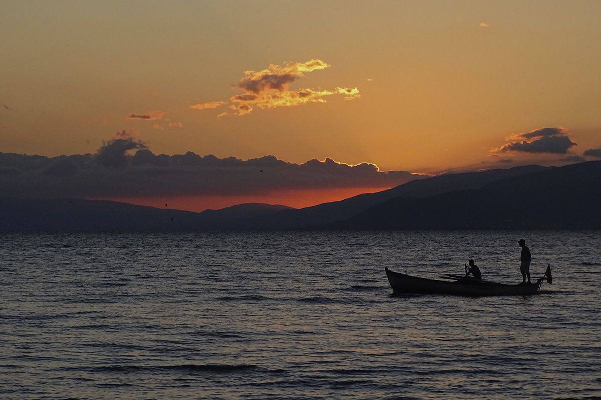 Gün batımında İznik Gölü'nde kayıkla balık tutan iki kişi